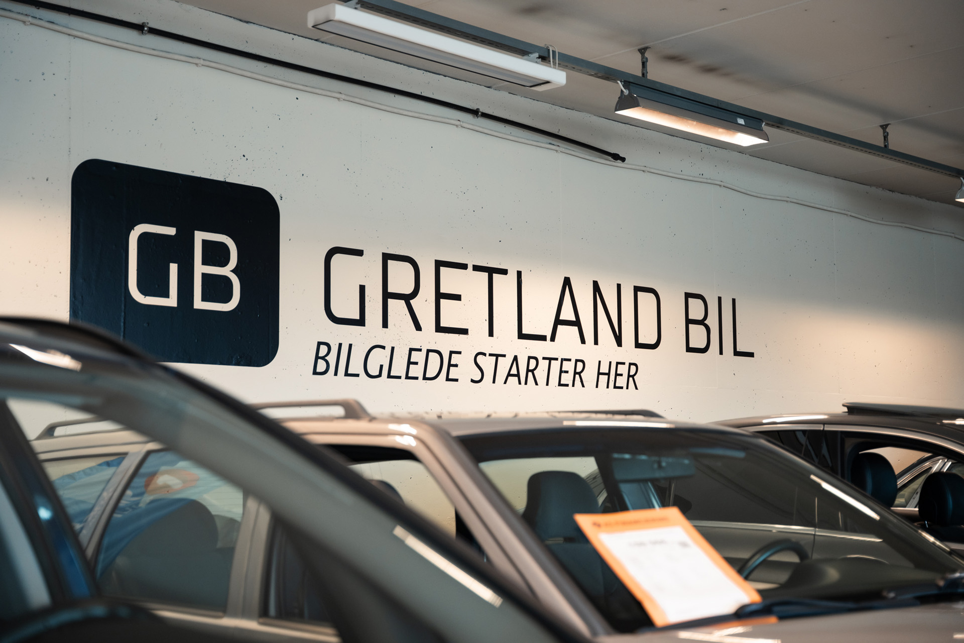 "Gretland Bil - Bilglede starter her" logoen til Gretland Bil AS med slagord på veggen i bilbutikken